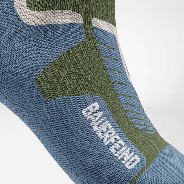 Nahaufnahme einer blau-olivgrünen Skisocke von Bauerfeind mit unterschiedlich gestrickten Zonen an Knöchel und Spann