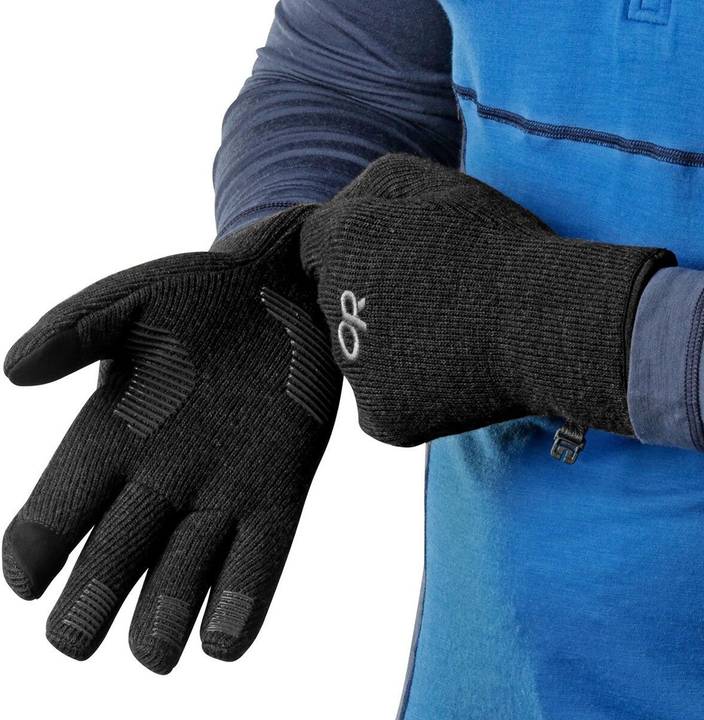 Person in blauem Funktionsshirt zieht einen grauen Strickhandschuh mit dunklen Fingerkuppen an