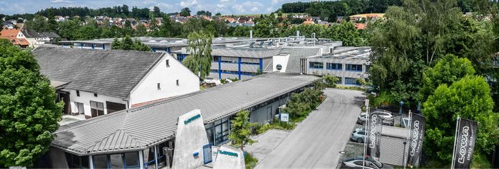 Luftbild des Lowa-Firmensitzes in Jetzendorf mit Werkshallen, Fahnen mit Lowa-Logo und dem Ort im Hintergrund