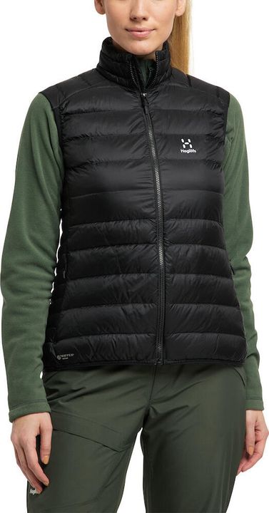 Frau trägt eine schwarze Haglöfs-Daunenweste über einem grünen Fleecepullover