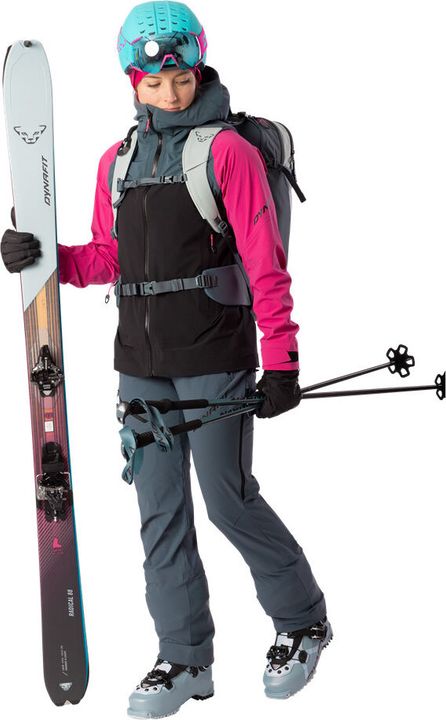 Skitourengeherin in pink-schwarzer Jacke mit Tourenski, Stöcken, Helm und Rucksack