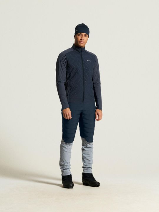 Mann in dunkelblauer Craft-Langlaufjacke, grauer Hose und Stirnband, Ganzkörperansicht