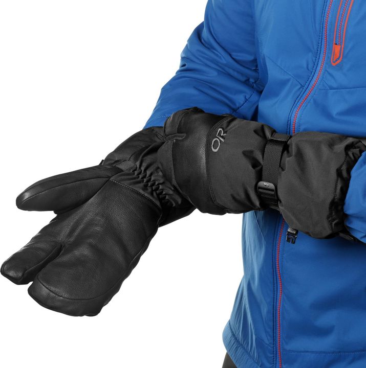 Person zieht die lange Stulpe eines schwarzen Dreifinger-Handschuhs über den Ärmel einer blauen Jacke