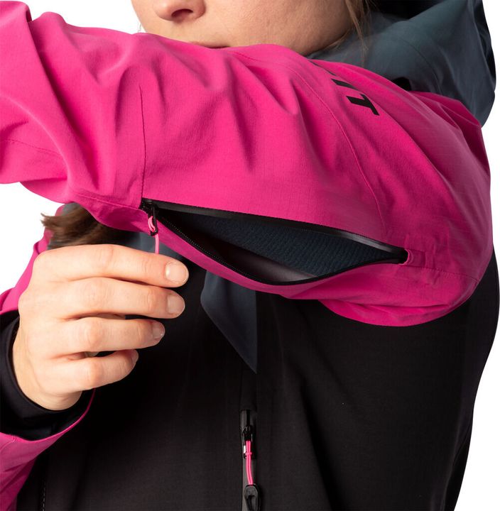 Hand öffnet die Brusttasche einer pink-schwarzen Dynafit-Skitourenjacke