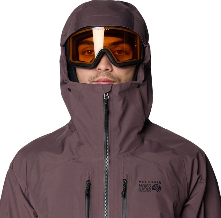 Freeskijacke von Mountain Hardwear in Mauve, Kapuze über Helm und orangefarbener Skibrille