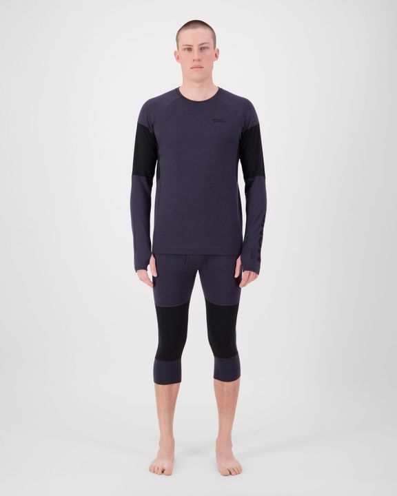 Mann in dunkelblauem Langarmshirt und 3/4-langer Unterhose von Mons Royale steht barfuß im Studio