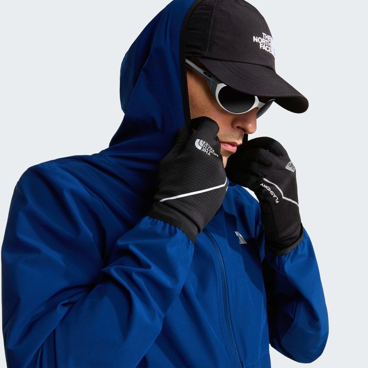 Läufer in blauer Jacke mit Kappe zieht einen schwarzen Handschuh an