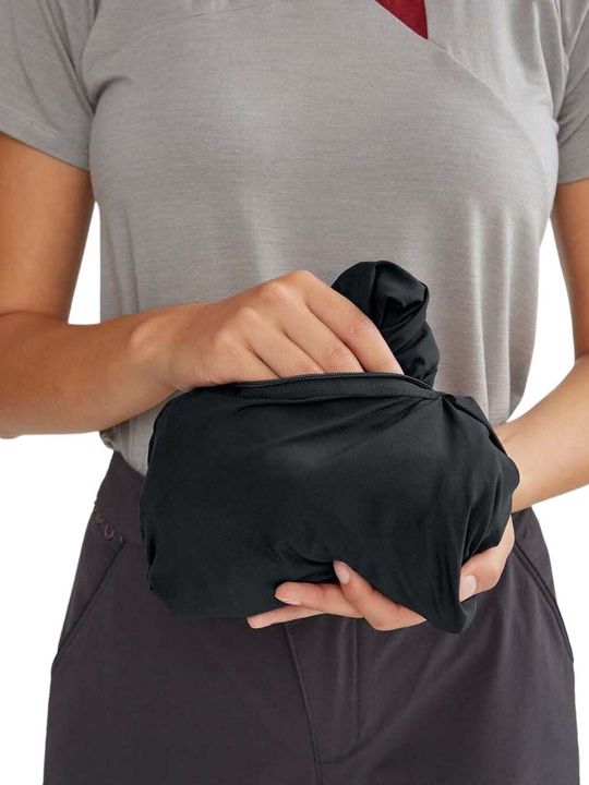 Person hält eine klein zusammengepackte schwarze Jacke vor dem Bauch
