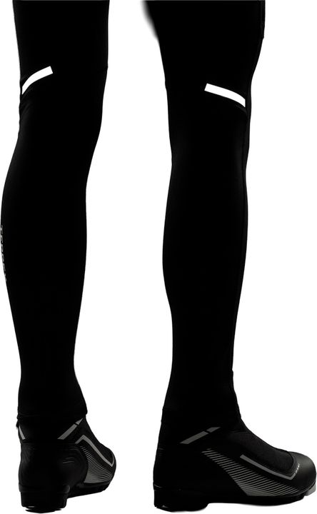 Beine in einer schwarzen Tight von adidas Terrex mit reflektierenden Streifen oberhalb der Knie, dazu Langlaufschuhe