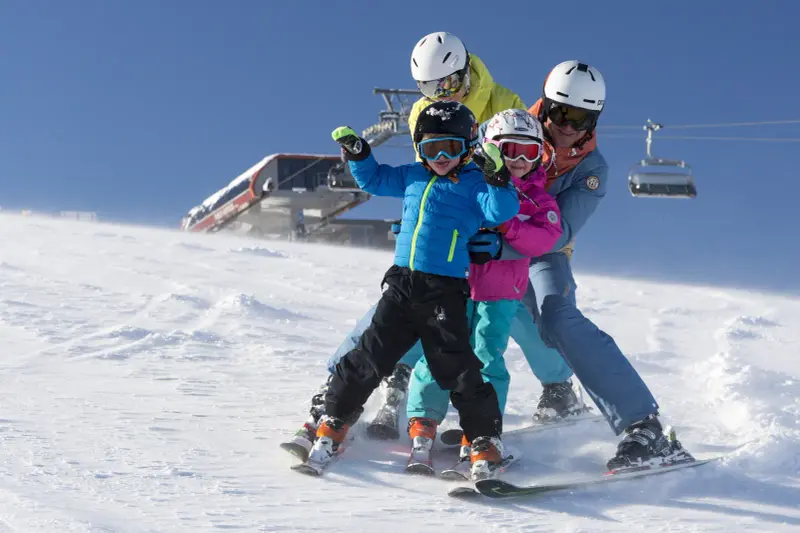 Eltern und zwei Kinder fahren gemeinsam Ski in der Almenwelt Lofer